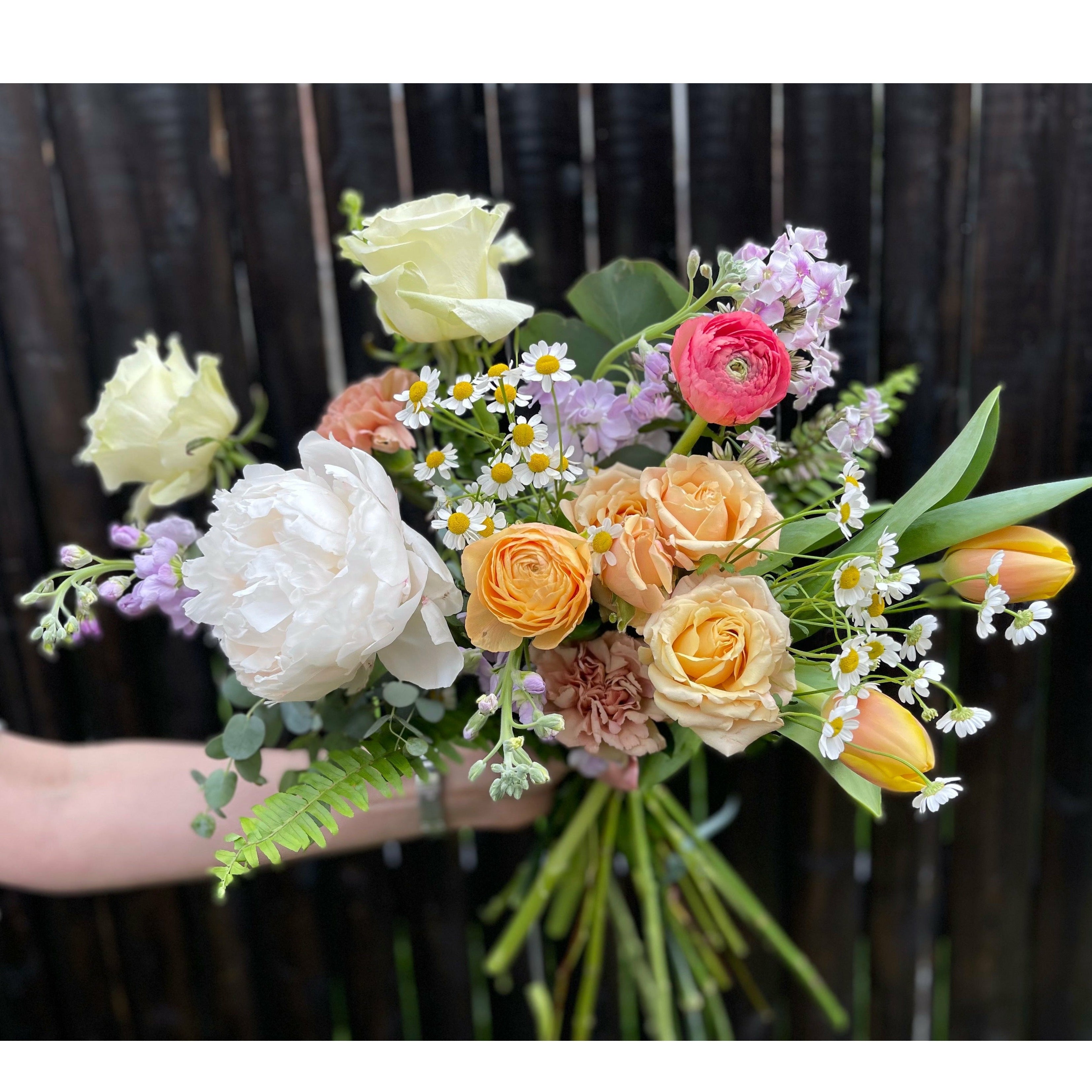 Bouquet of colorful flowers including roses and daisies with a blurred background